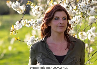 Beautiful White Woman Portrait In Spring Between Blossoming Fruit Trees At Sunny Weather Not Looking At Camera