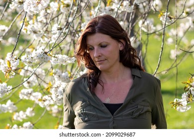 Beautiful White Woman Portrait In Spring Between Blossoming Fruit Trees Not Looking At The Camera