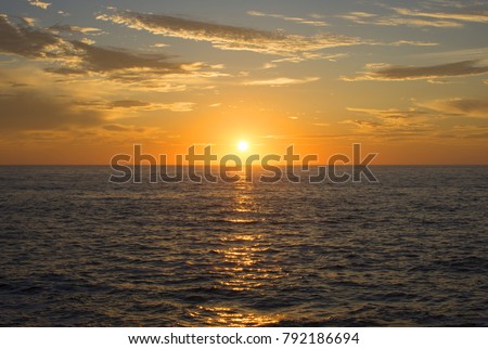 Beautiful wide angle setting golden sun centered over choppy ocean horizon