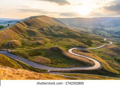 Schöne kurvenreiche Straße und Hügel bei Sonnenuntergang im Peak District - Landschaftssicht mit goldenem Licht in Großbritannien - Natur- und Reisekonzepte, Hintergrund bereit Bild