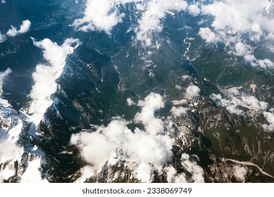 Beautiful window view of fluffy clouds and Alps mountains from passenger seat on airplane. Travel and air transportation