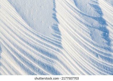 Beautiful winter background with snowy ground. Natural snow texture. Wind sculpted patterns on snow surface. 