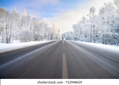 beautiful winter landscape with asphalt road,forest and blue sky.  frozen wintry day and path drive.
