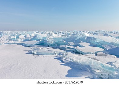 Beautiful Winter Landscape Of Frozen Lake Baikal. Endless Snow-covered Field With Transparent Blue Ice Floes On Ice Hummocks On A Frosty Sunny Day. Natural Cold Background. Empty Space For Text