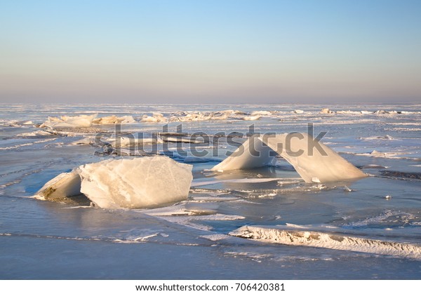 A beautiful winter landscape, ice\
blocks on the shore of a frozen lake, ice\
layering