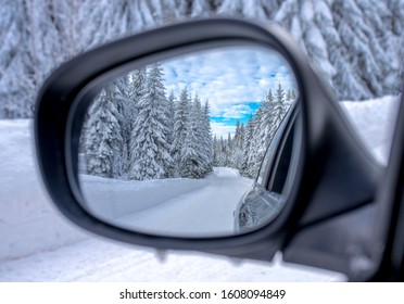 Beautiful winter landscape with snowy fir trees in car rear view mirror. Winter travelling concept - Powered by Shutterstock