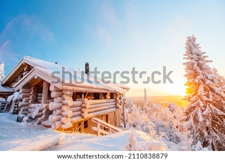 Beautiful winter landscape with wooden hut and snow covered trees at sunset in Lapland Finland