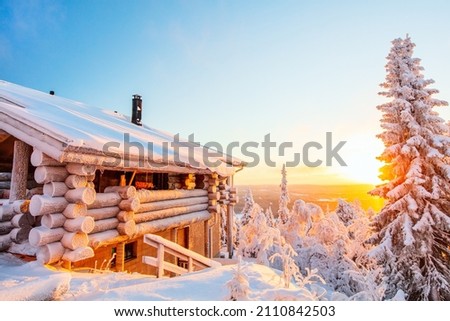 Beautiful winter landscape with wooden hut and snow covered trees at sunset in Lapland Finland
