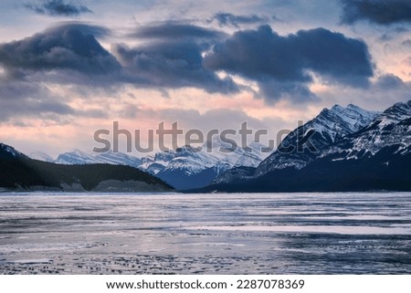 Beautiful winter scenery of Sunrise over rocky mountains and frozen lake in Abraham Lake at Jasper national park, AB, Canada