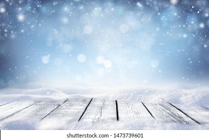 Beautiful winter snowy blurred defocused blue background and empty wooden flooring. Flakes of snow fall and sparkle on light, copy space. - Shutterstock ID 1473739601