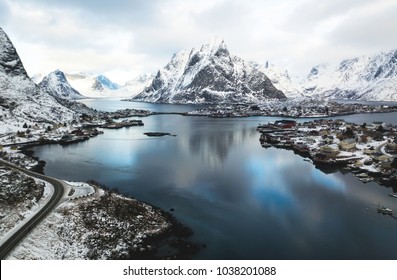 Beautiful winter snowy wide-angle summer aerial view of Reine, Norway, Lofoten Islands, with skyline, mountains, famous fishing village with red fishing cabins, Moskenesoya, Nordland, shot from drone
