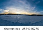 Beautiful winter sunset with rare nacreous clouds known as rainbow clouds over frozen lake Akaslompolo in Finnish Lapland.