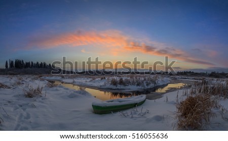 Beautiful winter sunset at the river. The boat in snow at the river in the winter