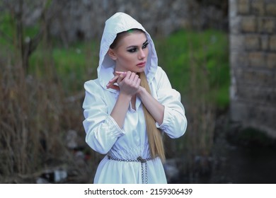 A Beautiful Witch Girl Stands By The River Of Water Performs The Ritual Spell Curse, Pagan, Satanist, Magician, God