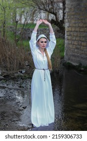 A Beautiful Witch Girl Stands By The River Of Water Performs The Ritual Spell Curse, Pagan, Satanist, Magician, God