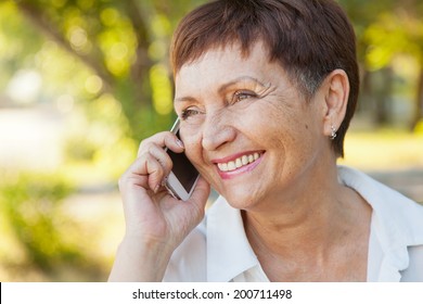 Beautiful Woman Of 50 Years With A Mobile Phone Outdoors