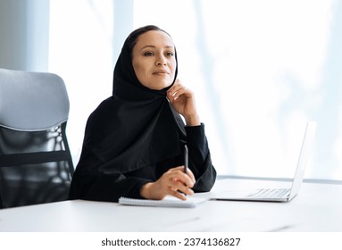 Beautiful woman with abaya dress working on her computer. Middle aged female employee at work in a business office in Dubai. Concept about middle eastern cultures and lifestyle - Powered by Shutterstock