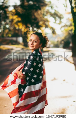 Beautiful woman with american flag. Portrait of young woman on running track holding american flag.