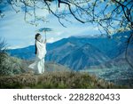 A beautiful woman in ancient Hanfu is standing under a pear tree on the hill
