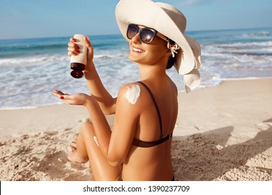 Beautiful Woman apply Sun cream on tanned  back. Skin and Body Care.Sun protection. Portrait of Female in Bikini using moisturizing sunscreen lotion and Sunblock. Girl Holding Suntan Lotion - Powered by Shutterstock
