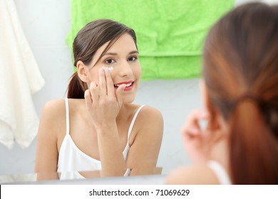 Beautiful Woman Applying Cream On Face At Bathroom