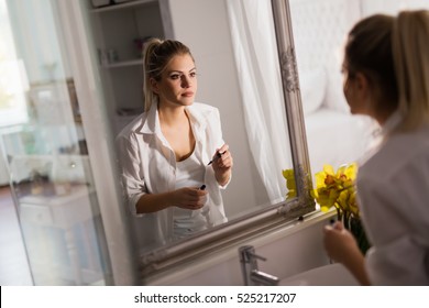 Beautiful woman applying makeup at home