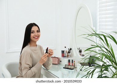 Beautiful woman applying makeup near mirror in room - Powered by Shutterstock