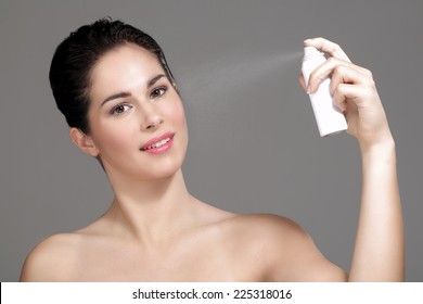 Beautiful Woman Applying Spray Water On Face On Neutral Background