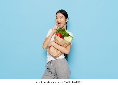 Beautiful woman of Asian appearance pack with vegetables healthy food products - Powered by Shutterstock