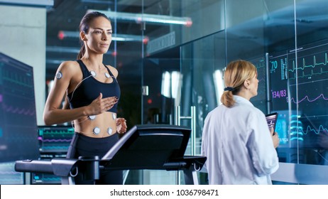 Hermosa atleta corre en un molino con electrodos atados a su cuerpo, una médica usa Tablet PC y controla los datos de EKG que se muestran en monitores de laboratorio.