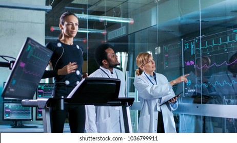 Beautiful Woman Athlete Runs on a Treadmill with Electrodes Attached to Her Body, while Two Scientists Supervise Watching EKG Data Showing on Laboratory Monitors. - Powered by Shutterstock