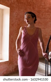 Beautiful woman in authentic retro twenties flapper dress and headband walking down an antique spiral staircase