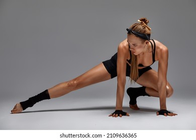 Beautiful Woman Ballet Dancer In Black Swimsuit Posing On Light Grey Studio Background. Animal Instinct