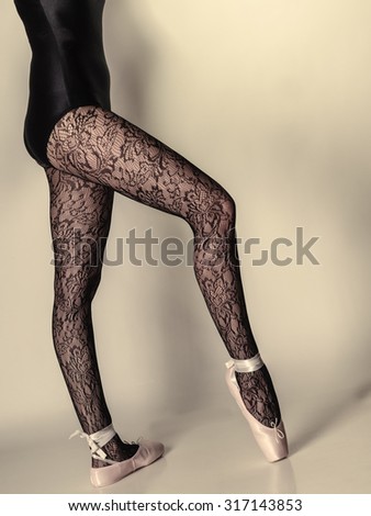 beautiful woman ballet dancer, part of body legs in shoes and black lace tights studio shot on gray background