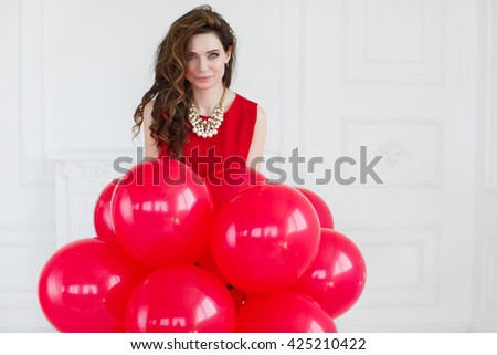 Beautiful woman with balloons. Fashion photo of beautiful woman with balloons. Studio photo. Portrait of a surprised happy woman in red dress holding balloons 