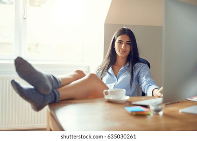 Beautiful Woman In Bare Legs And Socks With Feet On Table Or Wooden Desk Inside Home Based Office