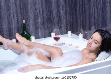 A Beautiful Woman In A Bath With Foam Drinking Wine