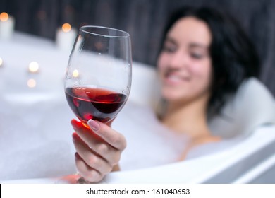 A Beautiful Woman In A Bath With Foam Drinking Wine