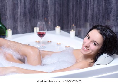 A Beautiful Woman In A Bath With Foam Drinking Wine