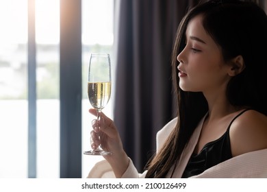 Beautiful Woman In Bathrobe With Glass Of Champagne At Bedroom Alcohol, Celebration And Drinking Alone Concept Asian Sexy Girl Sitting On Bed At Hotel Room With Holding Champagne Glass 