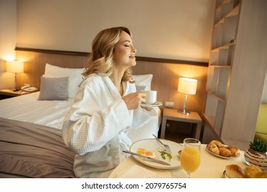 Beautiful woman in bathrobe having breakfast in the hotel room