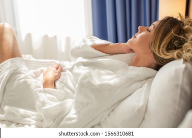 Beautiful woman in bathrobe relaxing in hotel bed