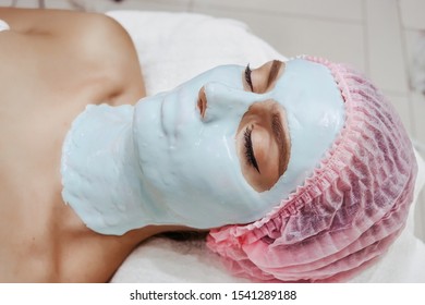 Beautiful woman in a beauty salon makes anti-aging alginate face mask