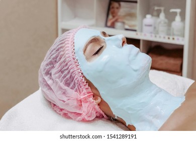 Beautiful woman in a beauty salon makes anti-aging alginate face mask