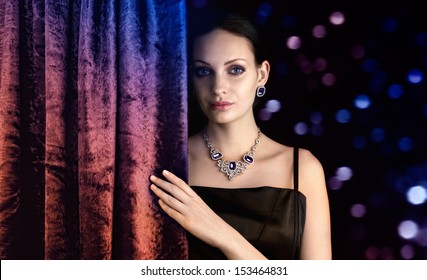 Beautiful Woman Behind The Curtain On Dark Background 