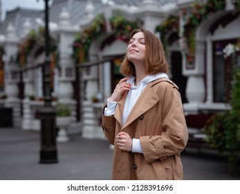 Beautiful Woman In Beautiful Beige Coat Walk In Autumn Cloudy Moscow, Enjoys Warm Rain Drops. Street Style. Travel To Russia Concept.