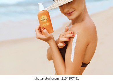 Beautiful Woman in Bikini Applying Sun Cream on Tanned  Shoulder. Sun Protection. Skin and Body Care. Girl Using Sunscreen to Skin. Portrait Of Female Holding Suntan Lotion and Moisturizing Sunblock.