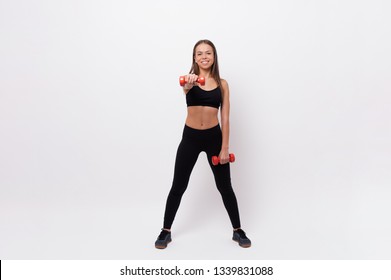 Beautiful Woman In Black Sportwear Doing Exercises With Dumbells Over White Background 