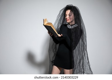 bella mujer con vestido negro de novia con velo de novia y un libro
