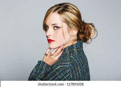 Beautiful Woman With Blond Hair In A Bun Wearing A Tweed Jacket And Red Lipstick On Grey Studio Background